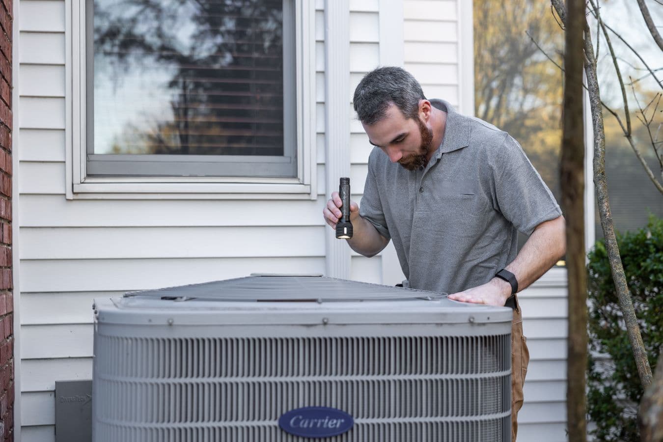 Técnico inspeccionando una unidad HVAC residencial